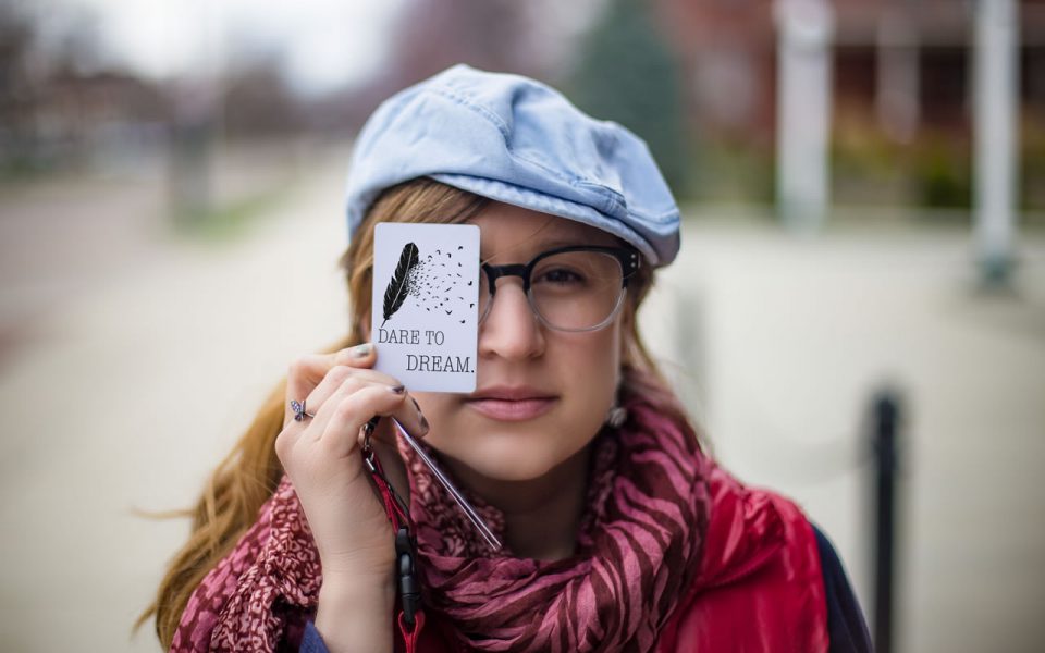 A student holding a card that says "dare to dream."