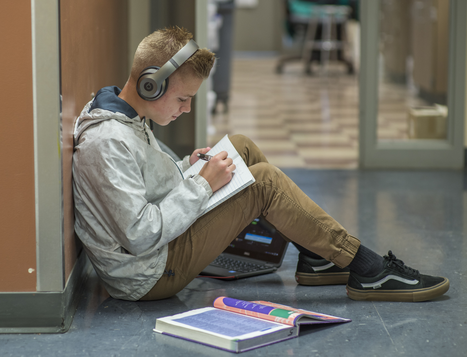 Student sitting in the hall with headphones studying