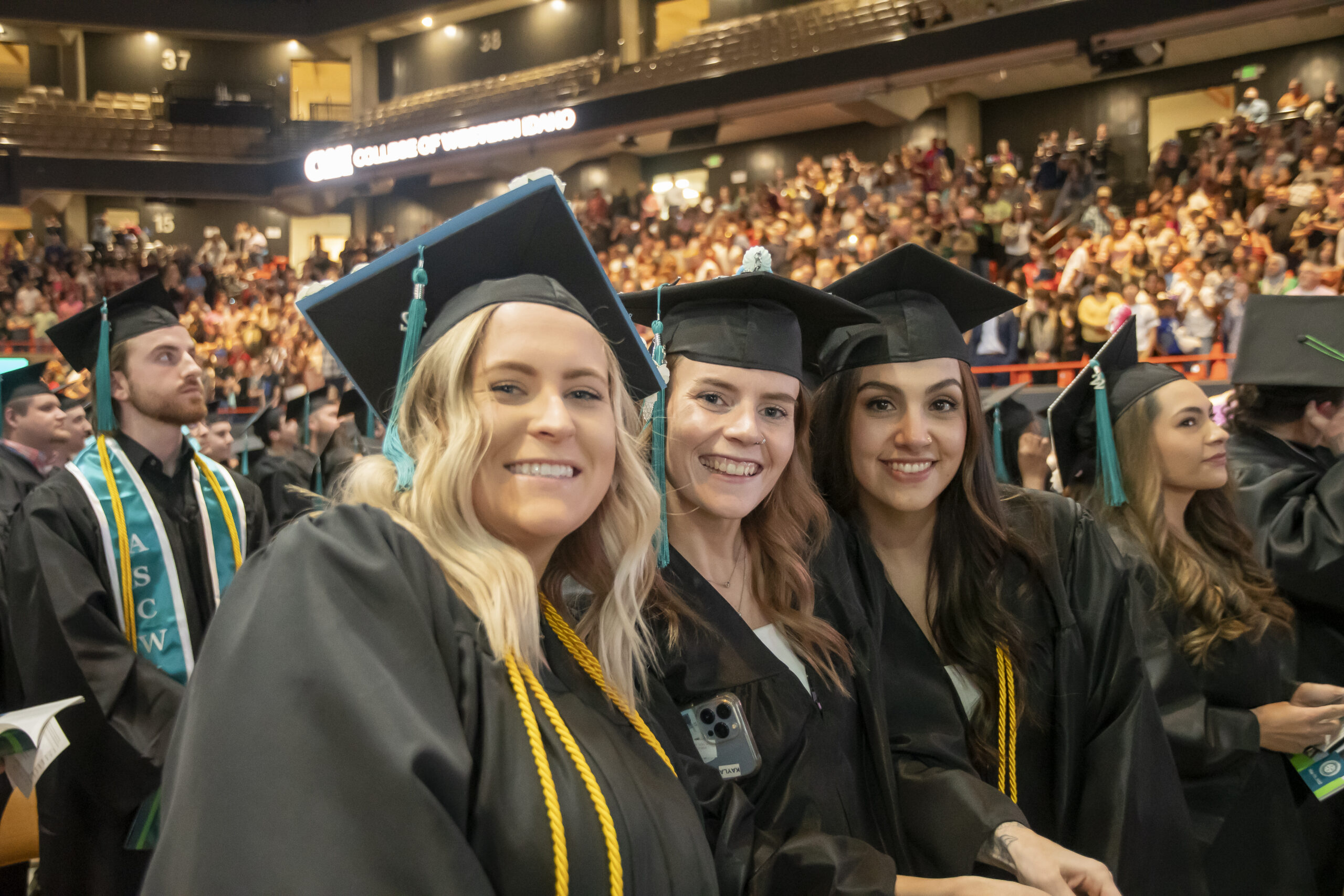 three students in graduation caps and gowns