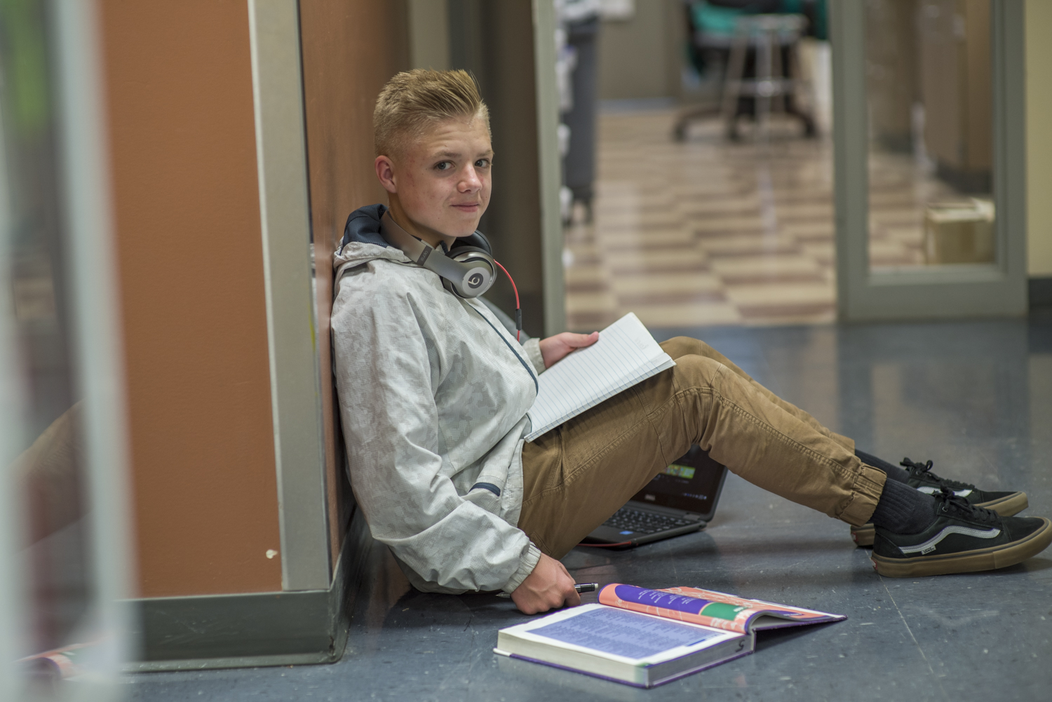 Student sitting on the follow of his school's hallway